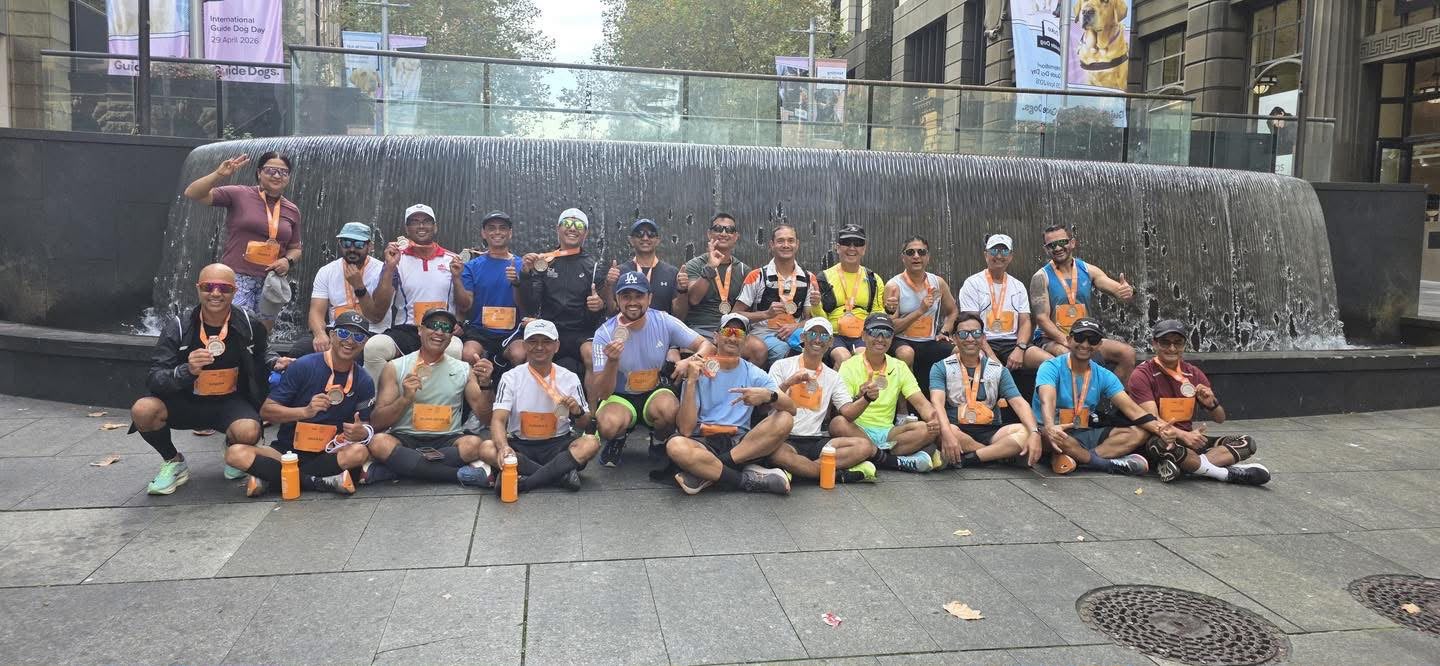 NRA runners with medals and orange bottles in front of a city fountain
